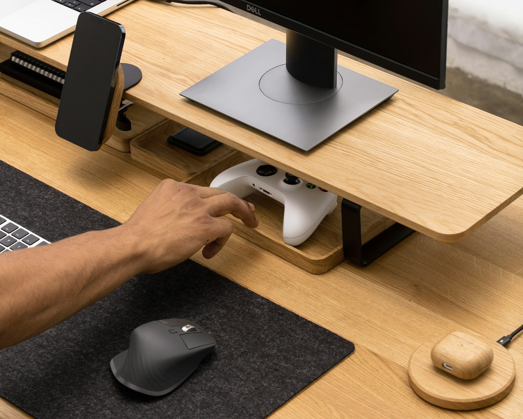 Organized wood desk with monitor riser, felt mouse pad, and wireless charger